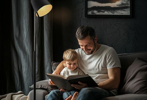 Header Bild zum Ratgeber Licht/Beleuchtung von Möbel Brügger. Ein Vater liest seinem Sohn aus einem Buch vor.