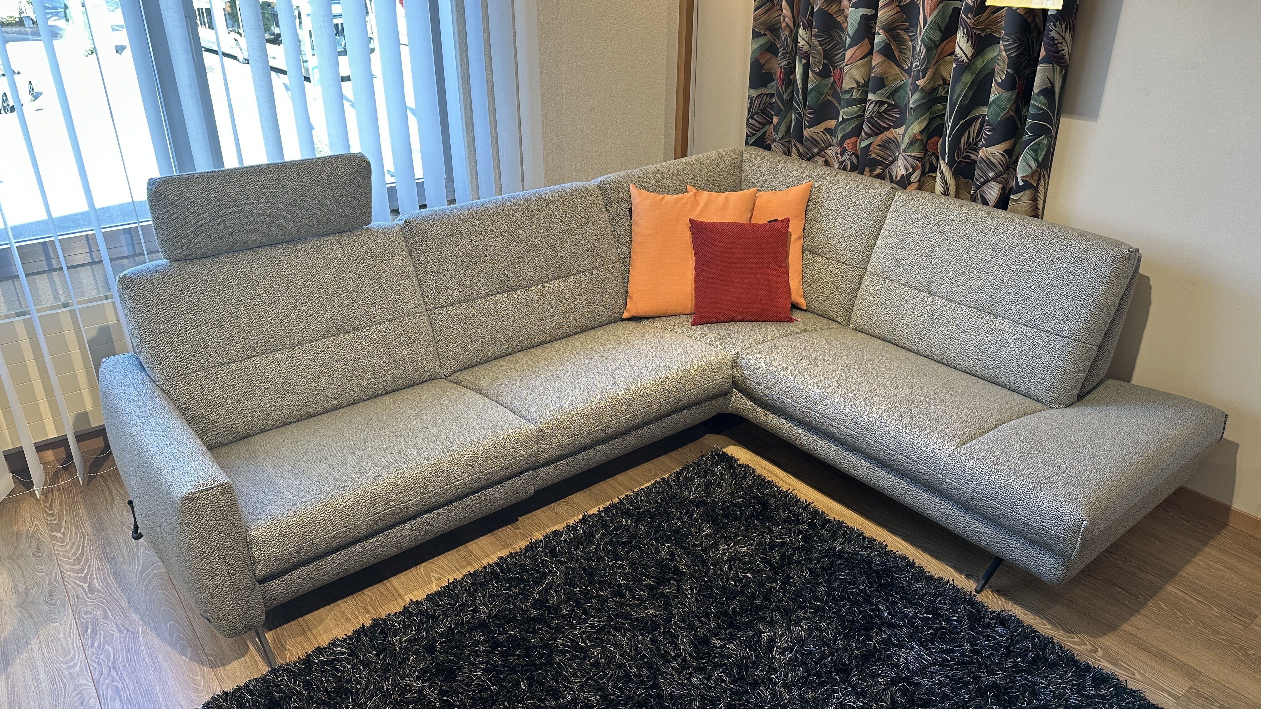 Ein modernes, stilvolles Ecksofa in einem beigen Stoffbezug. Die Polstergruppe hat eine L-Form.